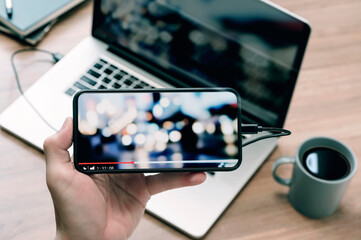 Closeup image of man hand holding smartphone and watching video in horizontal view.
