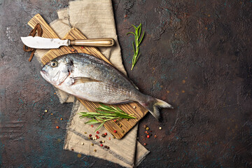 Fresh fish dorada or gilt-head bream on cutting board with spices and knife