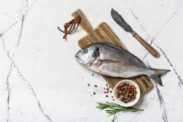 Fresh fish dorada or gilt-head bream on cutting board with spices
