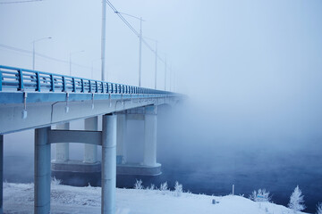 Winter frosty morning in Siberia. View of the bridge and river in the fog.