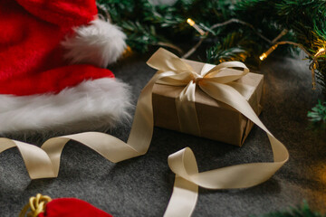 Christmas gift with Santa Claus hat and Christmas decorations on grey background with Christmas lights