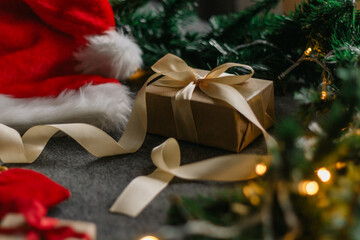 Christmas gift with Santa Claus hat and Christmas decorations on grey background with Christmas lights