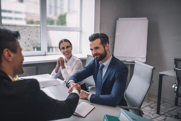Two men shaking hands and joyful woman