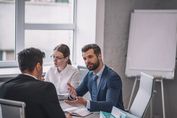 Two business men communicating at table and woman