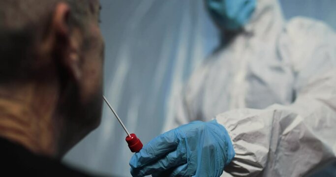 Medico con tuta bianca covid, mascherina e visiera fa il test del tampone laringeo