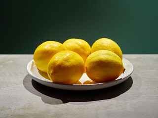 Lemons in a plate on a dark green background