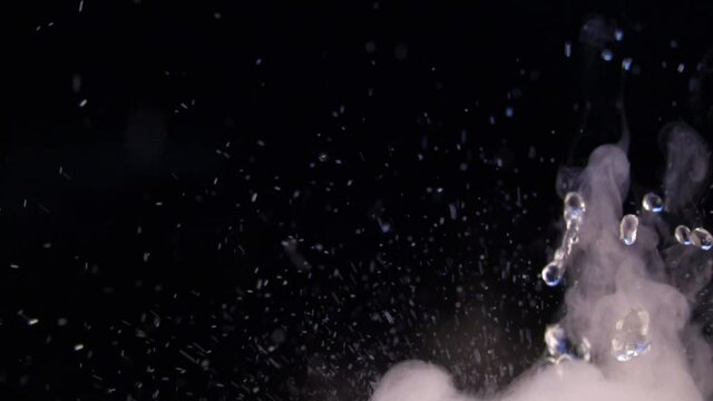 Relaxing videos with splashes and drops of water with fog or smoke on a black background with the ability to loop. Water splash in close-up.Swirl drip and jump water in motion.Chemical reaction water