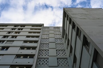 grey apartment tower with clouds and blue sky
