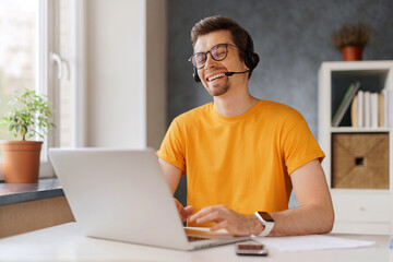 Happy laughing man wearing headset communicate by conference video call with friends or family....