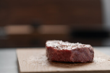 Raw ribeye steak spiced and ready to cook on oak board