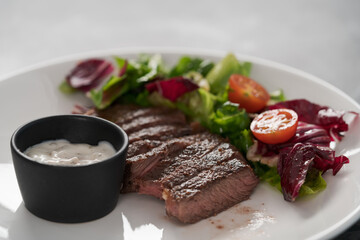 ribeye steak with garlic sauce and fresh salad closeup