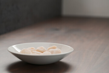 frozen scallops in white bowl on walnut table for defrosting