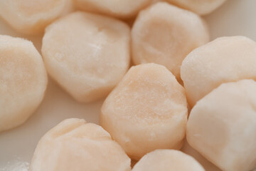 closeup of frozen scallops in white bowl on walnut table for defrosting