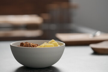 chocolate granola with mango and greek yogurt in white bowl on concrete background
