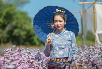 Portrait image of an asian woman with holding umbrella in a beautiful flower garden.