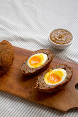 Homemade Scotch Eggs on a rustic wooden board, side view. Copy space.
