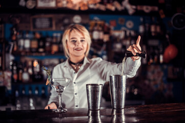 Confident girl bartender demonstrates his skills over the counter  