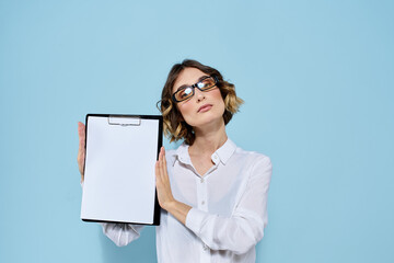 Business woman with documents in a folder on a blue background and in a light shirt glasses on her face