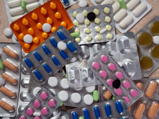 Medicines are randomly located on the surface. Tablets of different shapes and colors in blisters and in bulk. Medical background with pills for different diseases