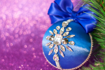 Blue Christmas ball in rhinestones for Christmas tree decoration. Christmas toy. Christmas toy for decorating a Christmas tree on a lilac background. Shining crystals on a blue ball.