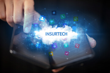 Businessman holding a foldable smartphone with INSURTECH inscription, technology concept