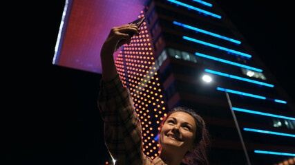 Happy lady using smartphone with beautiful bokeh in city vuilding background. Attractive young...