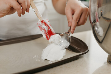 А close photo of the hands of a young woman who is putting the freshly whipped meringue on a tray...