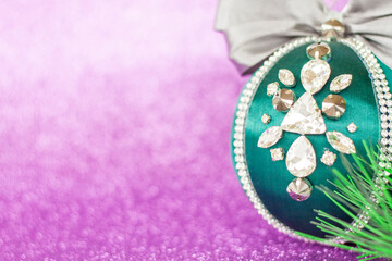 Green Christmas ball in rhinestones for decorating the Christmas tree. Christmas toy. Christmas toy for decorating a Christmas tree on a lilac background. Shining crystals on a green ball.