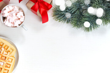 Christmas presents, fir branch, Viennese waffles and coffee with marshmallows on a white background. Winter Christmas holiday theme. Flat lay, top view. Copy space for text.
