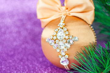 Golden Christmas ball in rhinestones for decorating the Christmas tree. Christmas toy. Christmas toy for decorating a Christmas tree on a lilac background. Shining crystals on a Golden ball.