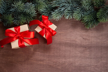 Christmas gifts and fir branches on a dark wooden background. Winter Christmas holiday theme. Flat lay, top view. Copy space for text.