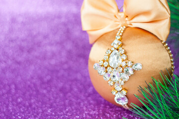 Golden Christmas ball in rhinestones for decorating the Christmas tree. Christmas toy. Christmas toy for decorating a Christmas tree on a lilac background. Shining crystals on a Golden ball.