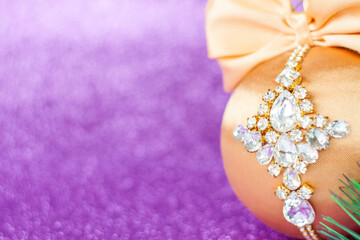 Golden Christmas ball in rhinestones for decorating the Christmas tree. Christmas toy. Christmas toy for decorating a Christmas tree on a lilac background. Shining crystals on a Golden ball.