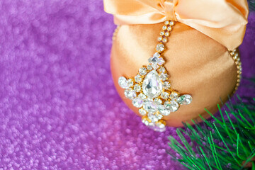 Golden Christmas ball in rhinestones for decorating the Christmas tree. Christmas toy. Christmas toy for decorating a Christmas tree on a lilac background. Shining crystals on a Golden ball.