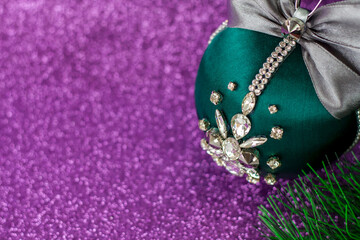 Green Christmas ball in rhinestones for decorating the Christmas tree. Christmas toy. Christmas toy for decorating a Christmas tree on a lilac background. Shining crystals on a green ball.