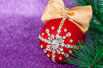 Red Christmas ball in rhinestones for Christmas tree decoration. Christmas toy. Christmas toy for decorating a Christmas tree on a lilac background. Shining crystals on a red ball.