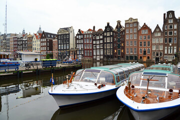 Famous vintage buildings of Amsterdam city. General landscape view at tradition Dutch architecture. Damrak canal in Amsterdam, The Netherlands.
