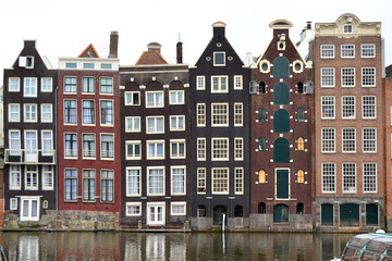 Fototapeta premium Famous vintage buildings of Amsterdam city. General landscape view at tradition Dutch architecture. Damrak canal in Amsterdam, The Netherlands.