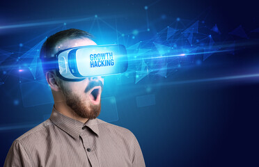 Businessman looking through Virtual Reality glasses with GROWTH HACKING inscription, cyber security concept