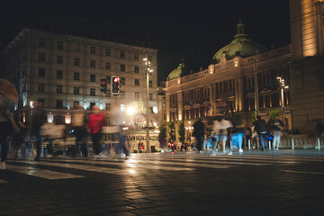Fototapeta na wymiar Pedestrian crossing in the historic center of Belgrade, blurred figures of people in the night city
