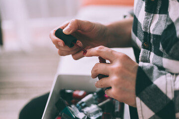 Woman painting nails with red nail polish at home, side view. Close up shot.