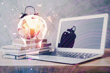 Computer on desktop in office with bulb icon hologram. Double exposure. Concept of idea.