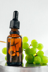 Grape seed oil in a glass bottle with ripe green grape