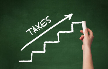 Hand drawing TAXES inscription with white chalk on blackboard, business concept