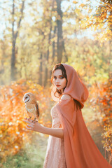 Portrait of fantasy girl princess walks with white bird barn owl on her hand. Beautiful mystical...