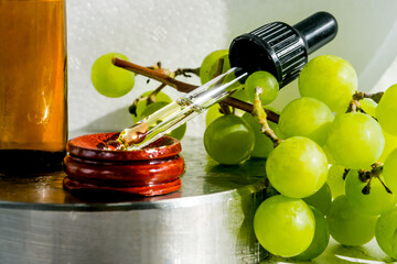 Grape seed oil in a glass bottle with ripe green grape