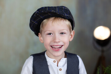 Portrait of positive little boy in cap against backdrop grey. Sincere child emotions. Happy child smile. Close Up face of happy smiling little boy. Portrait of cute little boy smiling at camera
