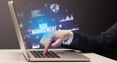 Businessman working on laptop with RISK MANAGEMENT inscription, new business concept