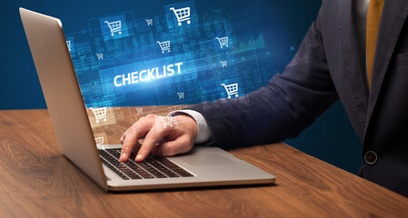 Fototapeta premium Businessman working on laptop with CHECKLIST inscription, online shopping concept