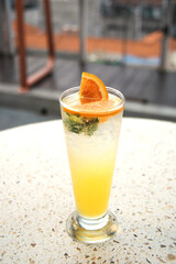 Homemade orange lemonade with mint in a tall glass, orange mojito